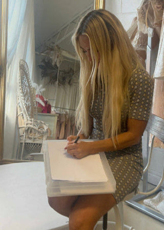 Woman sitting at a table writing in a notebook with a blurred background