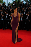 Woman in a purple dress on a red carpet with photographers in the background
