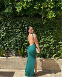 Woman in a green dress standing in front of a green hedge