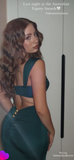 Woman in a green dress with a backless design, standing indoors.