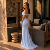 Woman in a light blue evening gown standing outdoors near a stone fireplace.