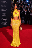 Woman in a yellow lace dress on a red carpet at the Cannes Film Festival.