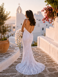 Woman in a white wedding dress with a scenic background of a church and white buildings.