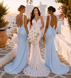 Three women in formal dresses standing on a stone path with a scenic background.