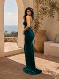 Woman in a green evening gown standing on a sunlit terrace with ocean view