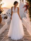 Woman in a white lace dress standing on a sunlit street with white buildings and flowers.