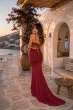 Woman in a red dress standing in a picturesque outdoor setting with ocean view.