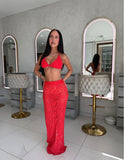 Woman in a red outfit standing in a stylish room with mirrors and furniture.