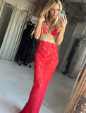 Woman taking a mirror selfie wearing a red lace outfit in a room with clothing racks.