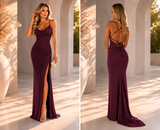 Woman in a burgundy evening gown with a high slit, shown from front and back, against a white architectural background.