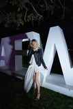 Person posing in front of large illuminated letters at night