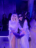 Two people posing together with a blue-purple hue in an indoor setting.