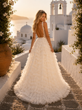 Woman in a white wedding dress with a feathered skirt standing in a picturesque Mediterranean village.