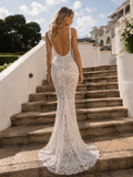 Woman in a white lace dress standing on stone steps with a scenic background