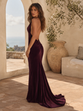 Woman in a purple evening gown standing in an outdoor setting with a scenic background.
