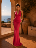 Woman in a red dress standing in a sunlit room with a scenic view of the ocean.