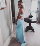Woman in a light blue dress standing in a room with a mirror and small table.